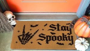 A doormat with a skeleton hand making "the shocker" says Stay Spooky
