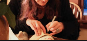 an artist draws on a Halloween mask with a pencil