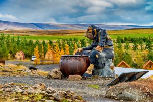 Grylla the Christmas troll from Iceland cooks with her pot in front of alpine hills