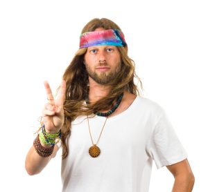 a bearded hippie young man with a headband makes a peace sign with his fingers