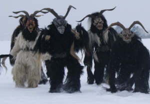 A group of Krampus looking individuals walk through the snow