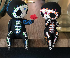 a dia de los muertos man skeleton holds a flower out to his female friend